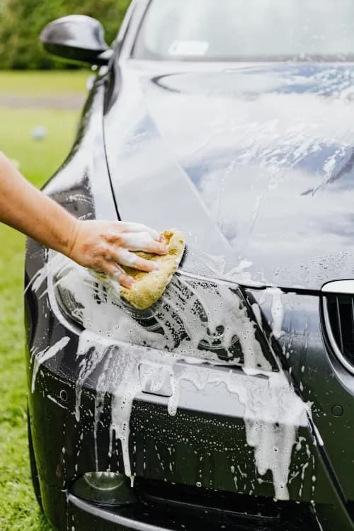 Hand-washing a car with a soapy sponge
